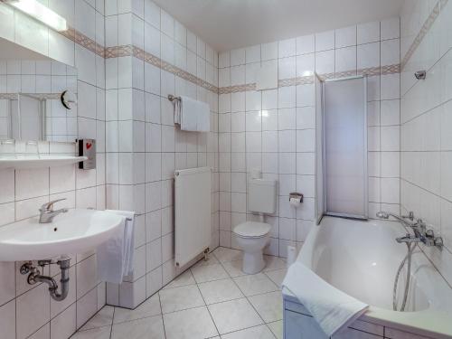 uma casa de banho com um lavatório, uma banheira e um WC. em Hotel Zur Burg GmbH em Burg Stargard