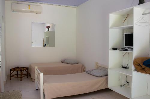 a small room with two beds and a tv at Hotel Fazenda Pé da Serra in Bom Sucesso