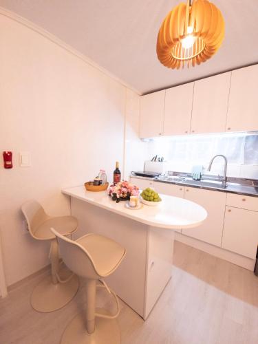 a kitchen with a white island with chairs and a sink at 화곡SongStay 무료짐보관 화곡역 도보5분 더현대서울 여의도 in Seoul