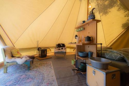 a tent with a dog laying on a chair in a room at Glampingtent Camping Namasté in Berlicum