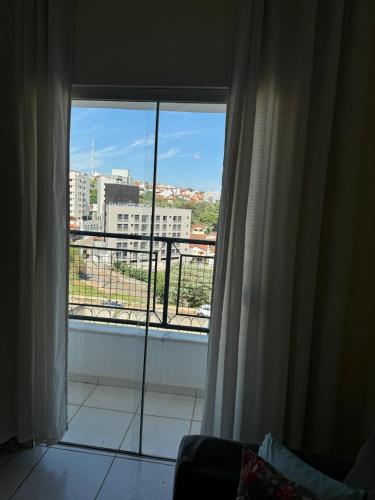 a room with a window with a view of a city at Apartamento com varanda in Lavras