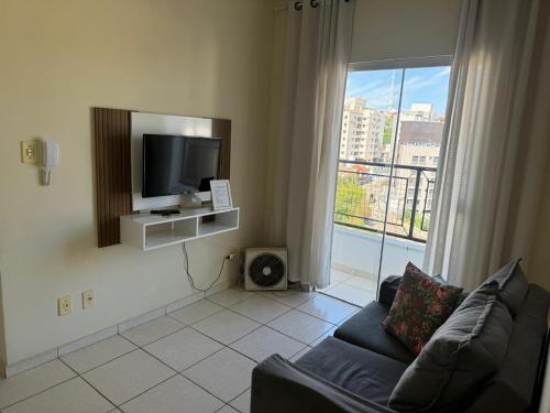 a living room with a couch and a flat screen tv at Apartamento com varanda in Lavras