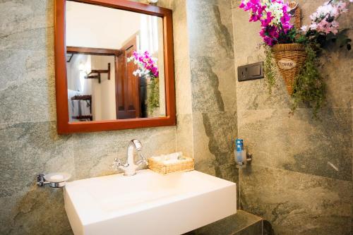 a bathroom with a sink and a mirror and flowers at Dutch Wall Fort in Galle