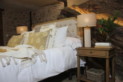 a bedroom with a white bed and a table with a lamp at HOTEL RURAL SANTUI in Horcajuelo de la Sierra