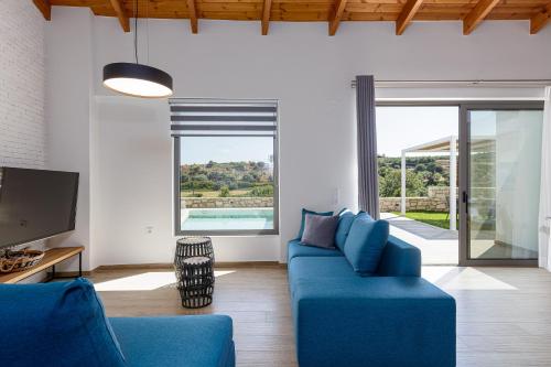 a living room with a blue couch and a tv at Eveland Accessible Villas in Sfakaki