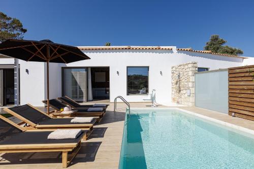 a pool with chairs and an umbrella next to a house at Eveland Accessible Villas in Sfakaki