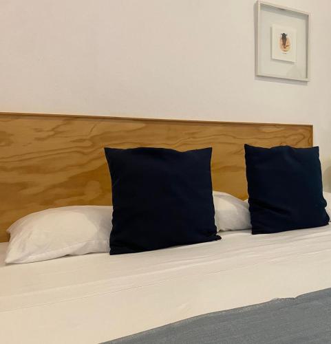 a bed with two pillows and a wooden headboard at Studios Downtown Cancun in Cancún