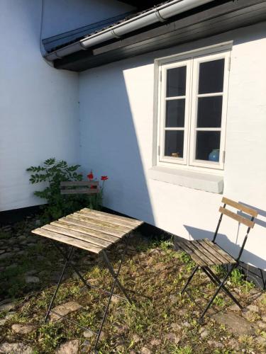 a picnic table and a chair in front of a house at Bakkely in Hjortshøj