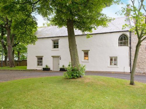 a white house with a tree in the yard at The Farmhouse in Easington