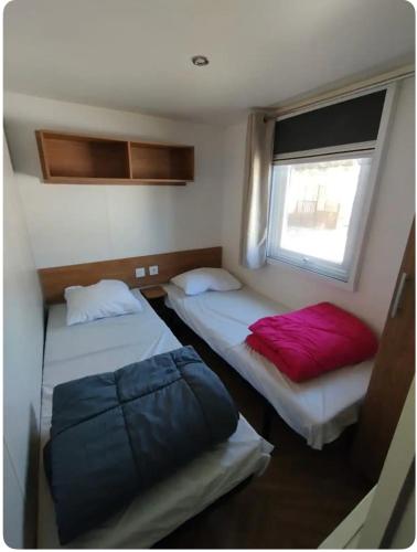 deux lits dans une petite pièce avec une fenêtre dans l'établissement Entre mer et montagne, à Canet