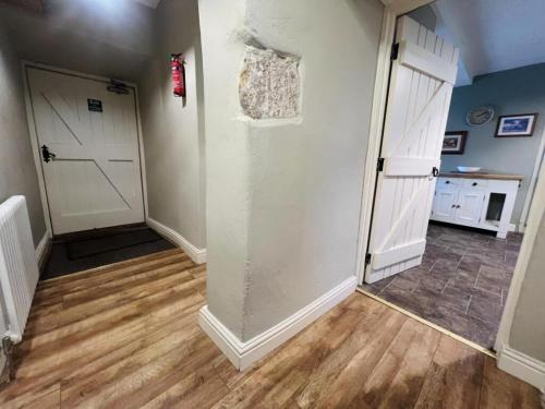 a hallway with a white door and wooden floors at The Farmhouse in Easington