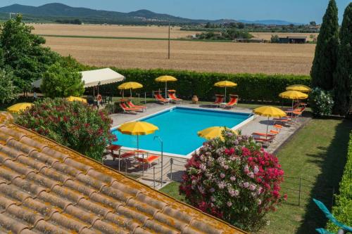 a swimming pool with umbrellas and chairs and a field at Podere Casalpiano Campiglia Marittima BARATTI POPULONIA Bella Tuscany in Casa Banditelle