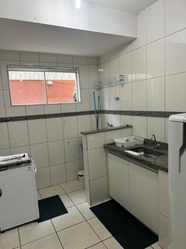 a white kitchen with a sink and a window at Aconchegante Apartamento in Lavras