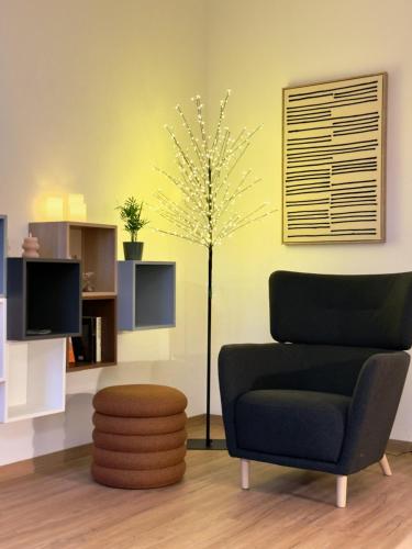 a living room with a chair and a tree at Feinzeit Lovely Lou - renovierter Altbau, Design, Zentrum! in Bamberg