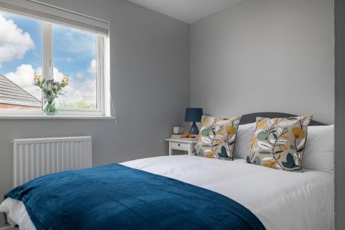 a bedroom with a bed with a vase of flowers on a window at Contemporary House Llanelli in Llanelli