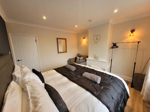 a bedroom with a bed and a couch at Modern 2 bed pet friendly Bungalow near countryside and a short drive to seafront- with large private garden by Catchpole Stays in Clacton-on-Sea
