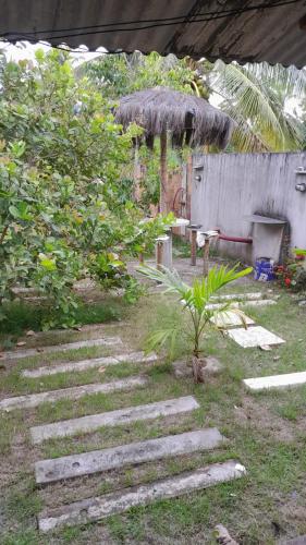 a pathway with a grass umbrella and a table and a bench at Casa no Guaibim in Valença