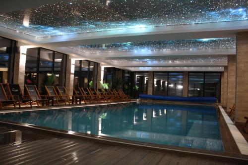 a swimming pool in a building with chairs at Silvani Kop NLux67, Milmari Apartments & Spa in Kopaonik