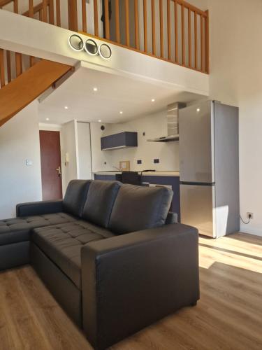 un salon avec un canapé noir et une cuisine dans l'établissement COMFORTABLE duplex en résidence SÉCURISÉE proche MÉTRO, à Toulouse