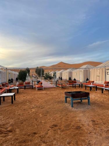 un gruppo di panchine in un campo con tende di Sahara Desert Camp a Merzouga