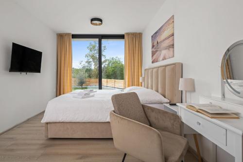 a bedroom with a bed and a desk and a television at Santalezi Sunset Villa - Nature and Private Pool in Santalezi