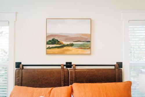 a painting hangs above a bed with orange pillows at Little River Retreat in Townsend