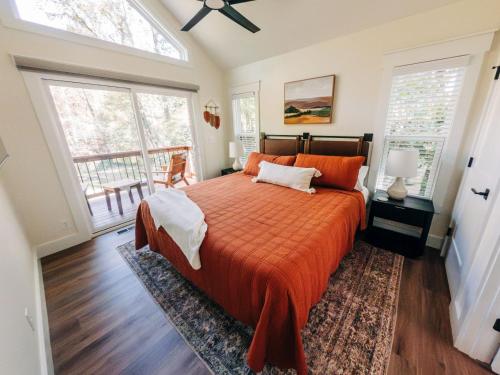 a bedroom with a bed with an orange comforter and two windows at Little River Retreat in Townsend
