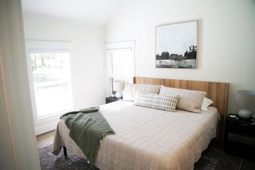 a bedroom with a bed with white sheets and two windows at Little River Retreat in Townsend