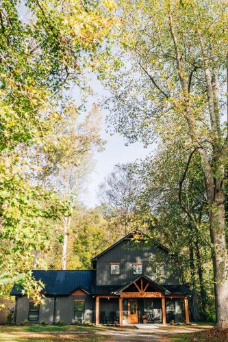 a black house in the woods with trees at Little River Retreat in Townsend