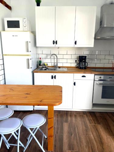 a kitchen with white cabinets and a wooden table at Apartamento Mar del norte, en Cotillo. in El Cotillo