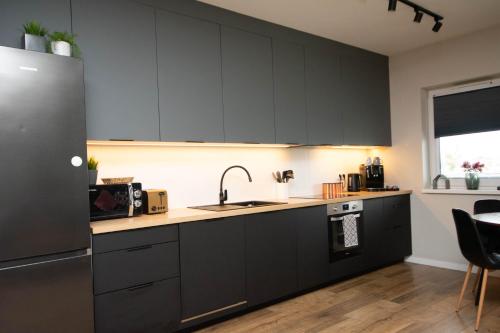 a kitchen with dark gray cabinets and a sink at Schneidemühl Premium Apartments in Piła
