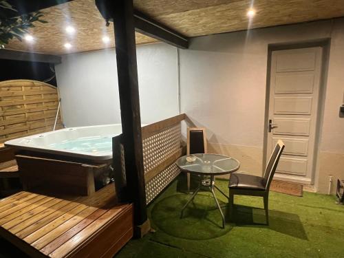 a room with a tub and a table and a chair at Le gîte du cavalier au cœur de la Forêt/jacuzzi in Dole