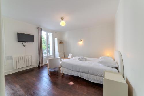 une chambre blanche avec un lit et une télévision dans l'établissement Golden République, à Paris