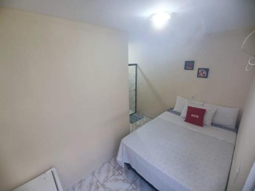 a small bedroom with a bed with a red pillow at Pousada Deus Provera in Maceió