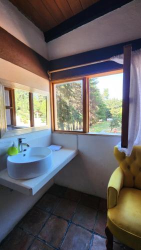 a bathroom with a sink and a window and a chair at La Villafranca del Cid in Zitácuaro