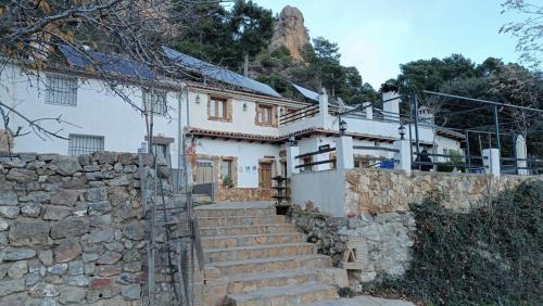 a white house with a stone wall and stairs at Dulce Posada in Cazorla