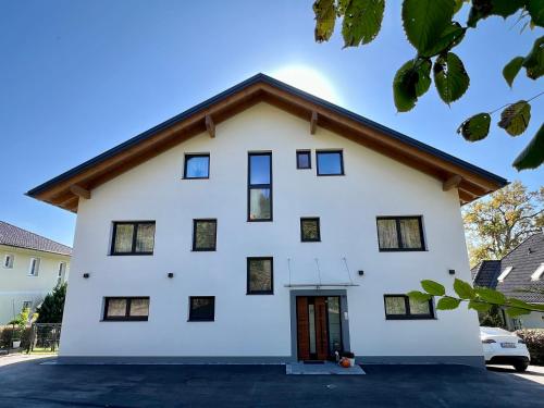 a white house with a brown roof at Apartments Sunnseitn by Gerrit & Herfried in Krumpendorf am Wörthersee