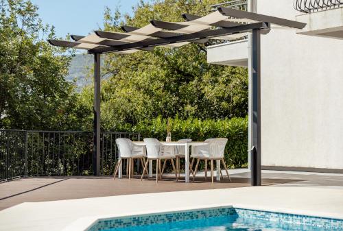 a table and chairs under a pergola next to a pool at Villa Sladovic in Herceg-Novi