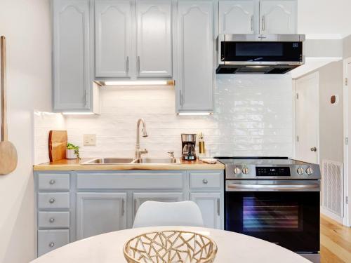 a kitchen with white cabinets and a sink and a stove at Bubbles in the Sand in Tybee Island