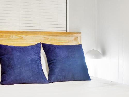 a bed with two blue pillows on top of it at Bubbles in the Sand in Tybee Island