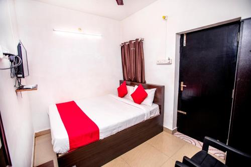 a small bedroom with a bed with red pillows at Hotel 1Square in Puducherry