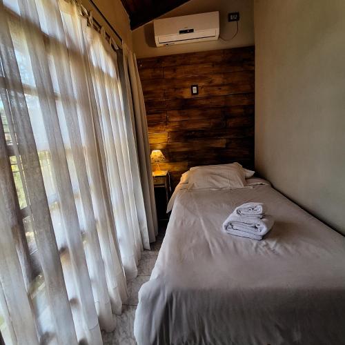 a bedroom with a bed and a window with curtains at Hotel Antiguo Camino in Villa General Belgrano