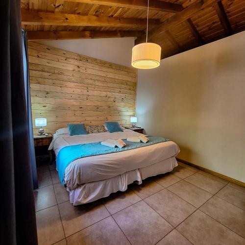 a bedroom with a large bed with a wooden wall at Hotel Antiguo Camino in Villa General Belgrano