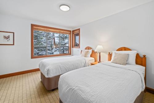 two beds in a hotel room with a window at Montebello by Whistler Premier in Whistler