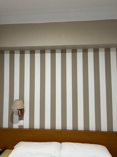 a bedroom with a bed and a striped wall at Pension Angelines, Sneuu Hostel Santander in Santander