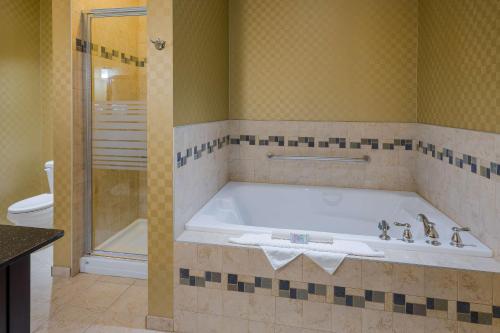 a bathroom with a tub with a shower and a toilet at Best Western Sunrise Inn & Suites in Stony Plain