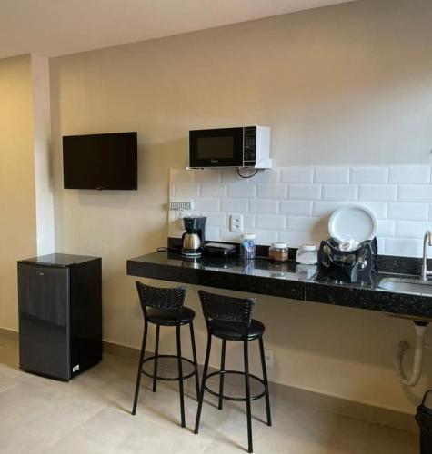 a kitchen with a counter and two bar stools at Morada do Sol Suítes in Arraial do Cabo