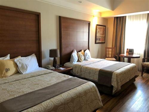 a hotel room with two beds and a window at Royal Palace in Hermosillo