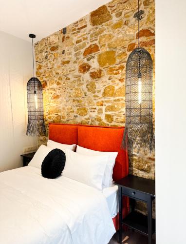una camera da letto con un letto bianco e un muro di pietra di Lithos Syros a Ermoupoli