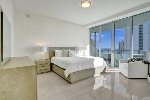 a white bedroom with a bed and a large window at 2BR Ocean Views Condo in West Palm in Riviera Beach